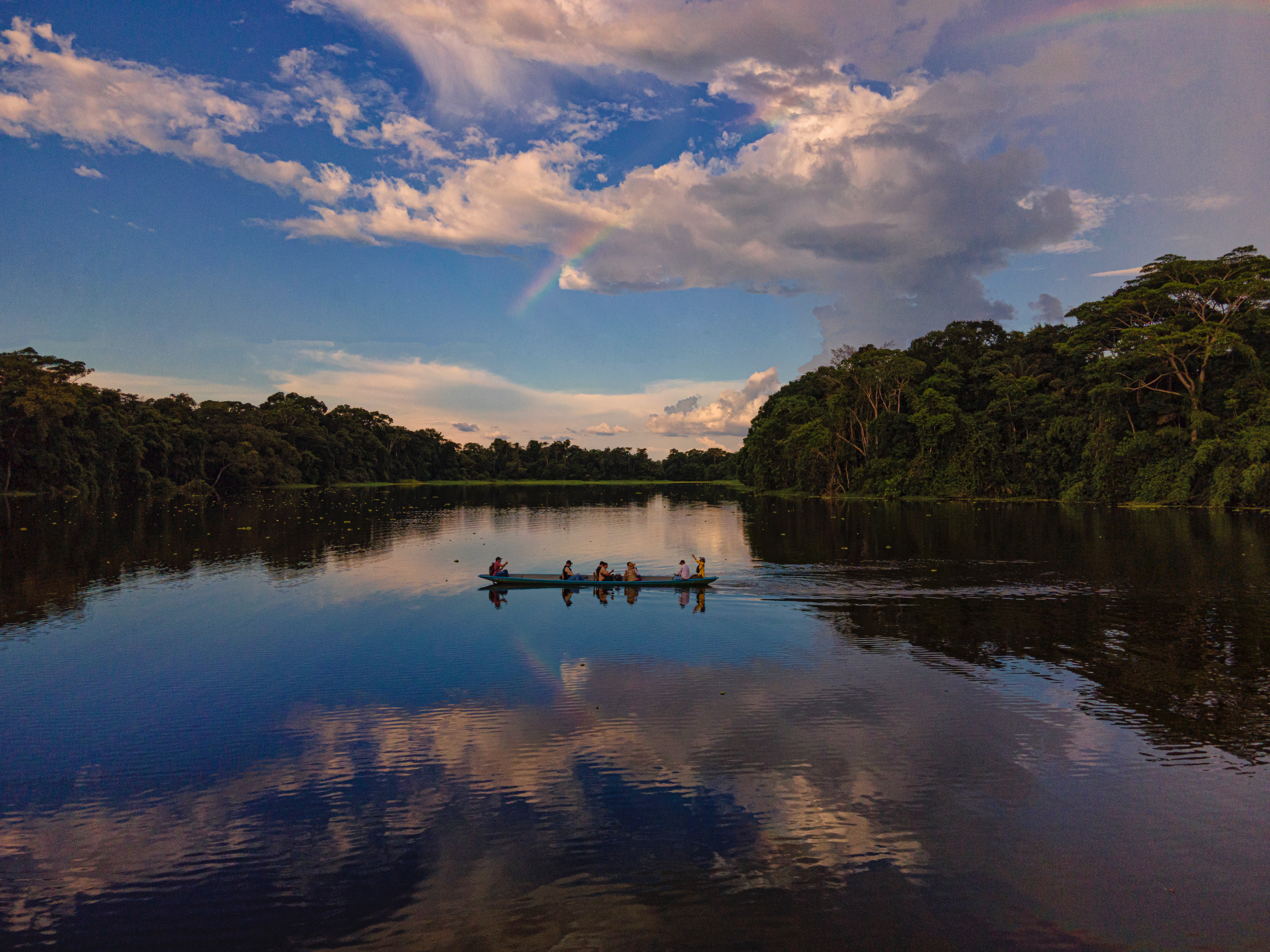 A canoe crosses a body of water in Ecuador beneath a blue sky.