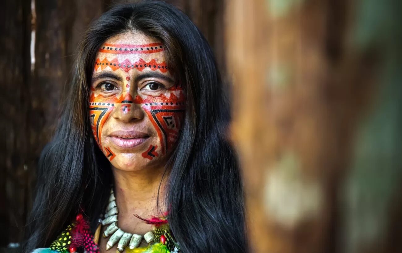 A woman in Ecuador smiles wearing colorful face paint.
