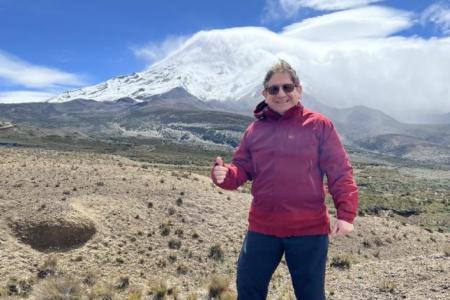 Photo of Fausto Sarmiento standing in front of a mountain, giving a thumbs-up